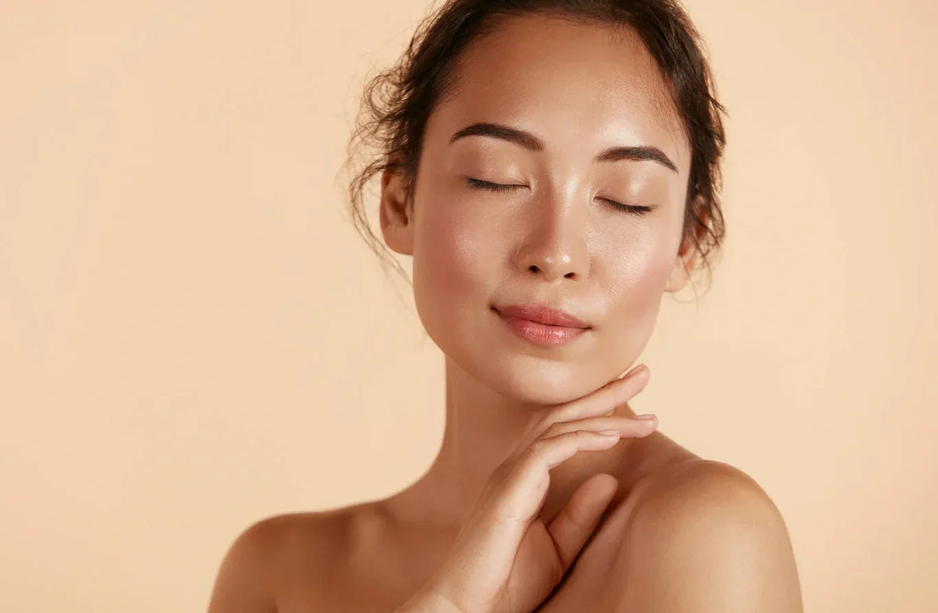 Woman with closed eyes touching her shoulder against a beige background