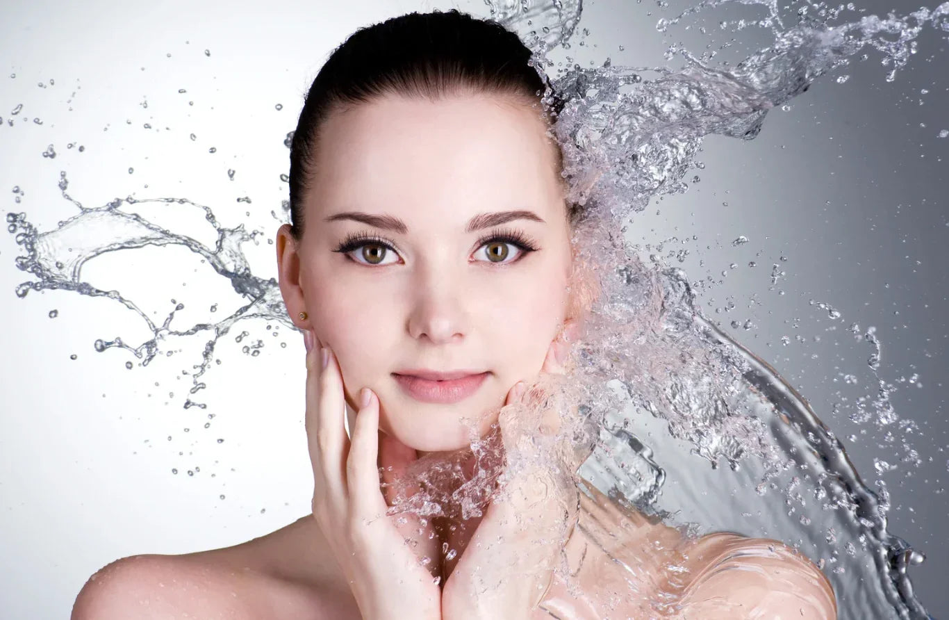 Woman with water splashes around her face on a gray background